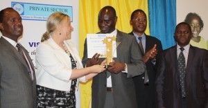World Bank Uganda office Country Manager, Ms Christina Malmberg Calvo (2nd left) hands Mr Basil Ajer, UIA’s Award plaque, as Mr Patrick Bitature, (PSFU Chairman of the Board) looks on. 